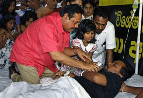 Sri Lanka's President Mahinda Rajapaksa offers a glass of water to his Housing Minister Wimal Weerawansa to end his hunger strike <font face=Arial size=-2>(Source: VOA)</font>