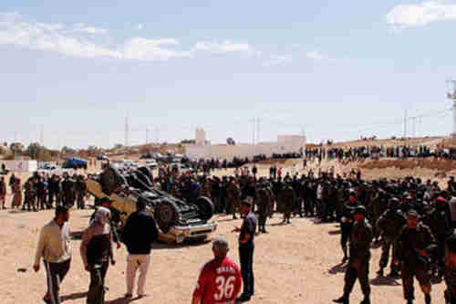 In Dehiba, people gather around overturned car belonging to Libyan army (CS Monitor)