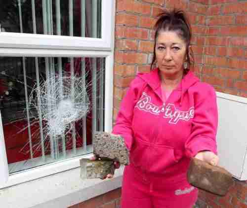 Belfast resident Anne-Marie Shanks beside windows that were smashed (Belfast Telegraph)