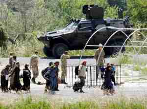 Syrian refugees pass Turkish military as they cross the border (AP)