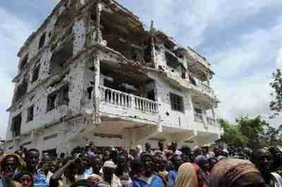 A group of internally displaced people crowd underneath a partially destroyed building in Mogadishu on Sunday (AFP)