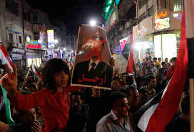 Palestinian girl in Ramallah holds poster depicting Assad with a red 'X' across his face. (Reuters)