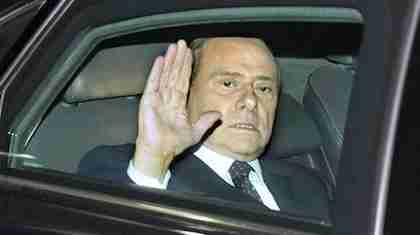 Berlusconi glumly waves to protesters (AP)