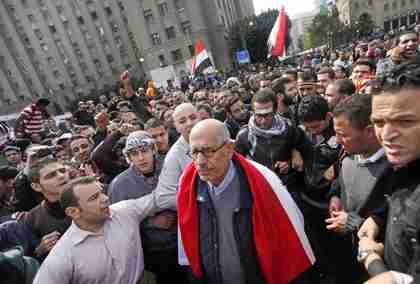 Pro-reform candidate and Nobel Peace Prize laureate Mohamed ElBaradei, draped in an Egyptian flag, is surrounded by protesters as he arrives for Friday prayers in Tahrir Square in Cairo. (AP)