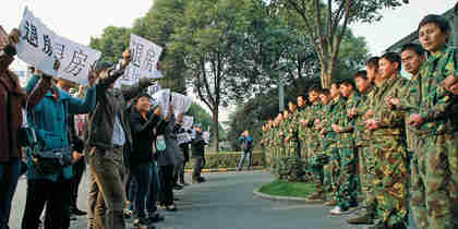 Homeowners face security guards as they rally in front of developers' sales office (Bloomberg)