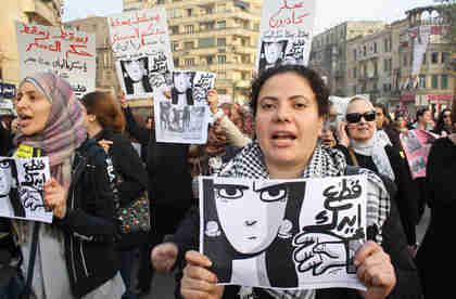 Women at Tuesdays march carrying banners depicting a womans face and the arm of a soldier that reads, 'Your hand should be cut off' (Ahram)