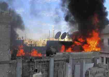 Flames rise from a house shelled by army in Baba Amr neighborhood in Homs (AP)