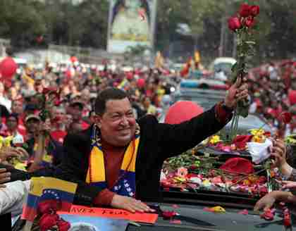 Hugo Chvez holds up flowers thrown by supporters in Caracas, just before he leaves for cancer surgery in Cuba (AP)