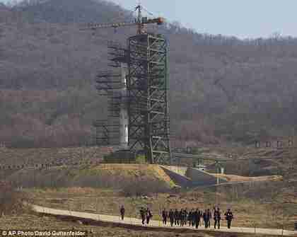 A group of journalists walk down a road in front of North Korea's Unha-3 rocket which it is expected to fire in the middle of April (AP)