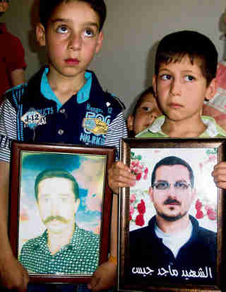 Syrian children holding portraits of their fathers, killed on Saturday by pro al-Assad forces (Reuters)