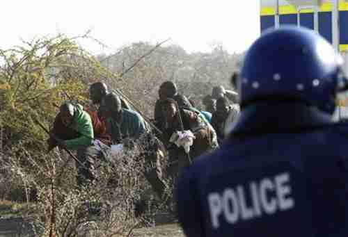 A policeman fires at protesting miners in South Africa on Thursday (Reuters)