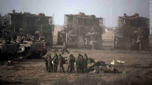 Israeli soldiers gather next to their armored bulldozers stationed on Israel's border with Gaza on Saturday, awaiting orders for the ground invasion (CNN)