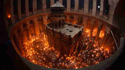 Worshippers hold candles lit by passing the 'holy fire' from candle to candle after midnight in Jerusalem on Sunday (Reuters)