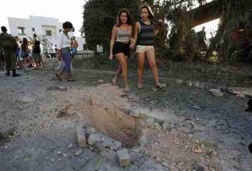 Two hot chicks walk past damage caused by a rocket fired from Lebanon into Israel (Reuters)