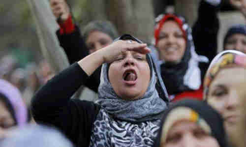  An Egyptian woman ululates as others wave a national flag in front of a polling station in Cairo on Tuesday (AP)