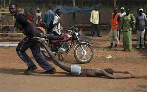 A man drags the corpse of the man who was lynched by CAR soldiers on Wednesday (AFP)