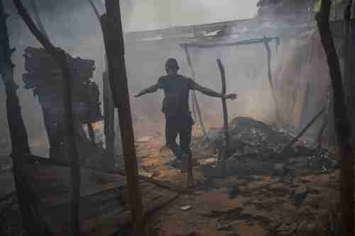 A Christian man runs through looted and burning homes of Muslims who have fled for their lives (Nat. Geographic)