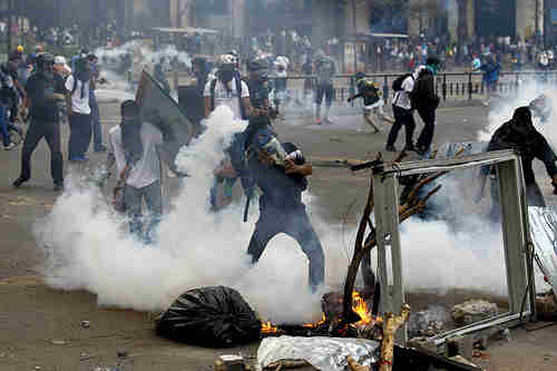 Protesters fight police in Caracas on Thursday (AFP)