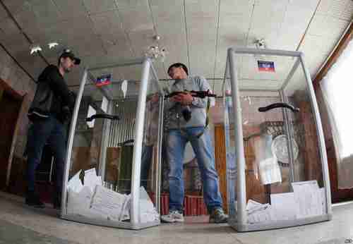 Armed Pro-Russian activists stand guard near clear plastic ballot boxes (AFP)