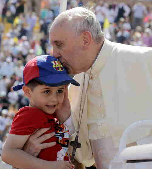 Pope Francis kisses a boy before celebrating a mass in Amman on Saturday (Getty)