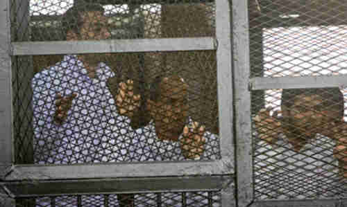 Caged Al-Jazeera journalists in court on Monday (AP)