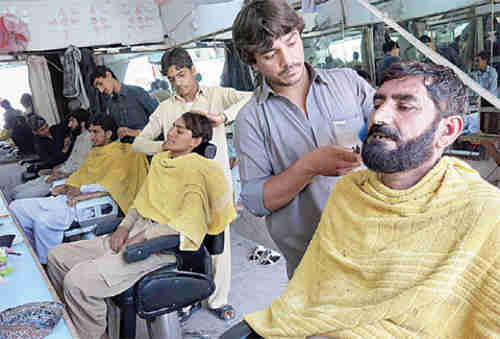 Taliban militants get their hair and beards trimmed so they won't look like killers (AFP)