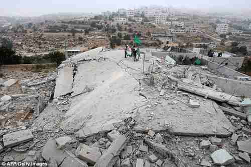 Hamas inspects the home of Hussam Kawasme, which was demolished by Israeli bombs.  Kawasme is a suspect in the June West Bank killing of three Israeli teens.  That killing triggered the Gaza war.  (AFP)