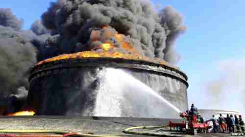 Flaming oil storage tank after being targeted with rockets by militias in Libya (Reuters)