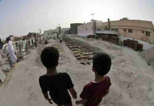 Two Shia Saudi boys stand at the graves of 21 people killed in the May 22 attack on a Shia mosque (EPA)