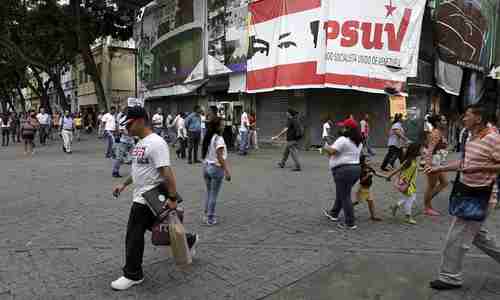 People walk past a billboard with Venezuelas United Socialist Party (PSUV) logo and an image of Chvezs Eyes in Caracas (Reuters)