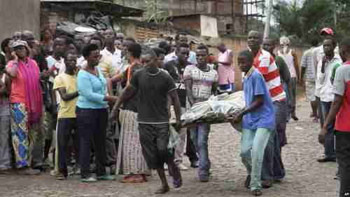 Men carry away a dead body in Bujumbura on Saturday (VOA)