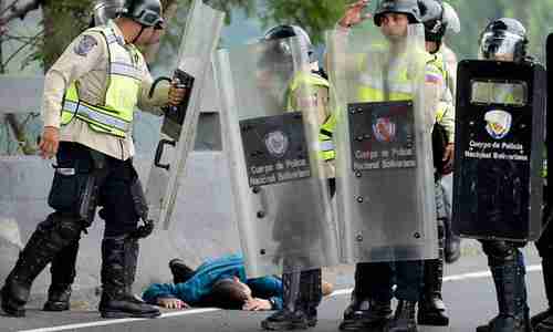 An injured man lies next to national guard members during a demonstration in Caracas, Venezuela on Wednesday (AFP)