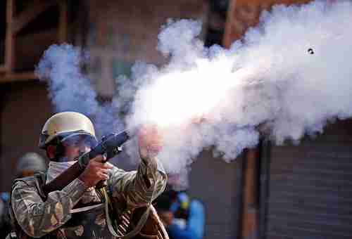 An Indian policeman fires a teargas shell at Srinagar, Kashmir, protestors on Tuesday (Reuters)