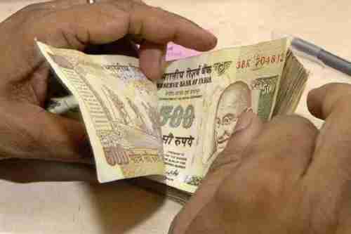 Man holding a wad of 500 rupee notes that have now become worthless paper (Reuters)