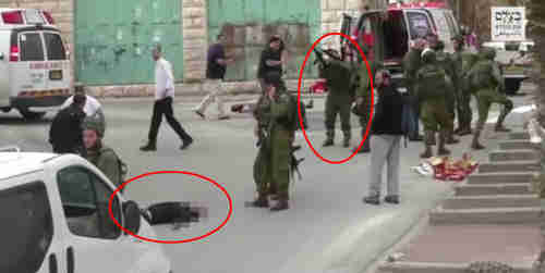 Screen grab from video of March 4, 2016.  Israeli soldier reloads his gun just before shooting dead the Palestinian lying wounded and bleeding (AP)