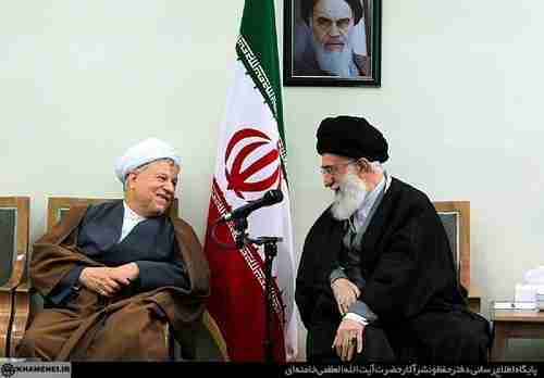 Hashemi Rafsanjani (L) shares a laugh with Supreme Leader Ali Khamenei, under a photo of the original Supreme Leader, Rouhollah Khomeini.  All three fought together in the 1979 revolution.