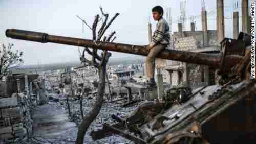 Boy sits on a tank turret amidst the destruction of Syria's war (AFP)