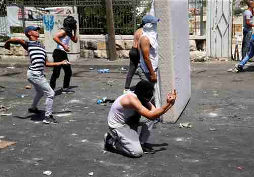 Palestinian protesters give Israeli security forces the finger during clashes in Jerusalem on Friday (Reuters)