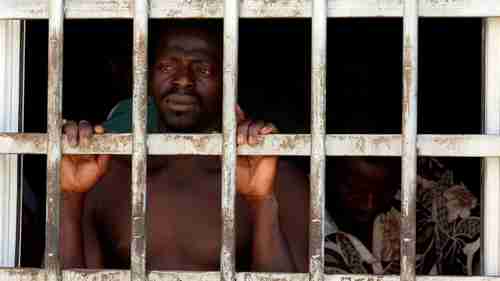 A migrant looks out of a barred door at a detention center in Gharyan, Libya, Oct. 12, 2017. (Reuters)