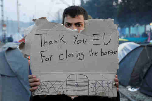  A migrant holds a sarcastic protest sign after failing to enter the EU (Reuters)