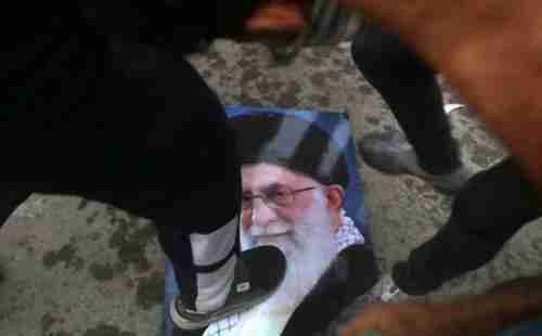 Protesters trample a portrait of Irans Supreme Leader Ayatollah Ali Khamenei, during the storming and burning of the Iranian consulate in Basra on Friday (AP)