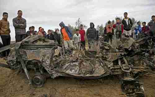 Palestinians stand next to the vehicle used in Sunday's military operation and destroyed by Israeli aircraft missiles on Sunday after the Israeli force had fled the scene.  (AFP)