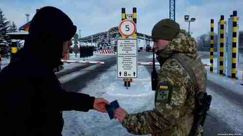 Ukrainian border guards prevent Russian men, aged 16-60, from entering Ukraine.  Sign says: 'Do not stop between the striped columns.' (RFE/RL)