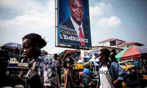 Women walk past a campaign poster of Joseph Kabilas chosen successor as president of DRC, Emmanuel Ramazani Shadary, in Kinshasa on Dec 18 (AFP)