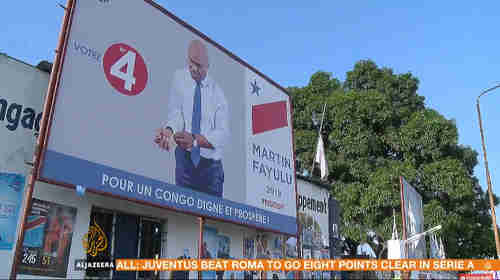 Leading opposition DRC candidate Martin Fayulu - campaign poster showing him buttoning or unbuttoning (I can't tell which) his shirt cuffs (Al-Jazeera)