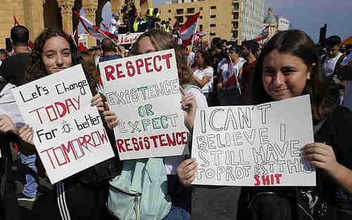 Girls holding anti-government placards during protests in Beirut, Lebanon, on Sunday (AP)