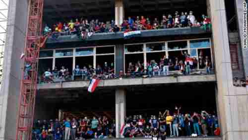  Anti-government protesters stand on a building in Baghdad last week (CNN)