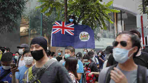 A protester displays the (British) Hong Kong colonial flag on Wednesday.  Under the new law, he could be sent to jail for 5 or more years.  (AP)