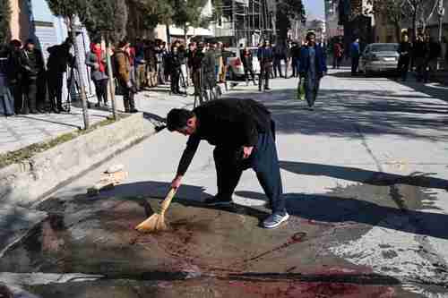 A Kabul resident washes the road after gunmen killed two female judges working for the Supreme Court (AFP)