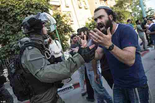 Israeli riot policeman tries to block a Jewish right-wing man as communal violence erupted in Lod on Wednesday (AP)